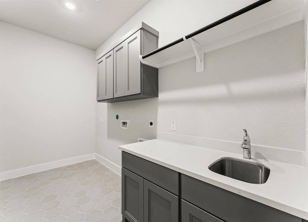 Utility Room with Washer and Dryer Connections, Sink, Hang to Dry Bar, Storage Cabinets, and Folding Area.