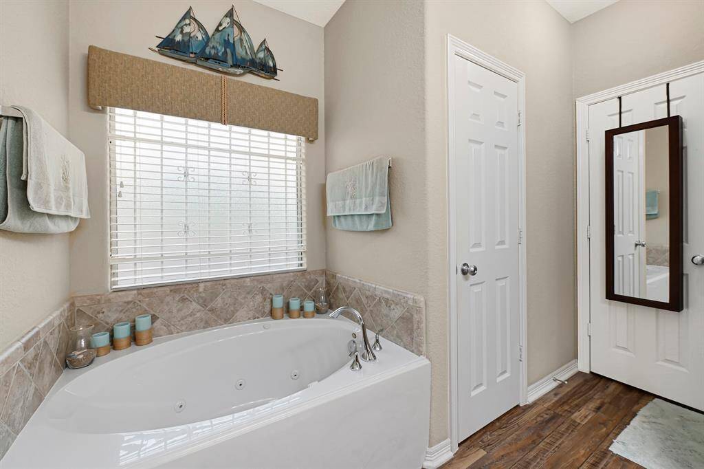 Relax in the spa-like primary bath featuring a deep jetted soaking tub with privacy window.