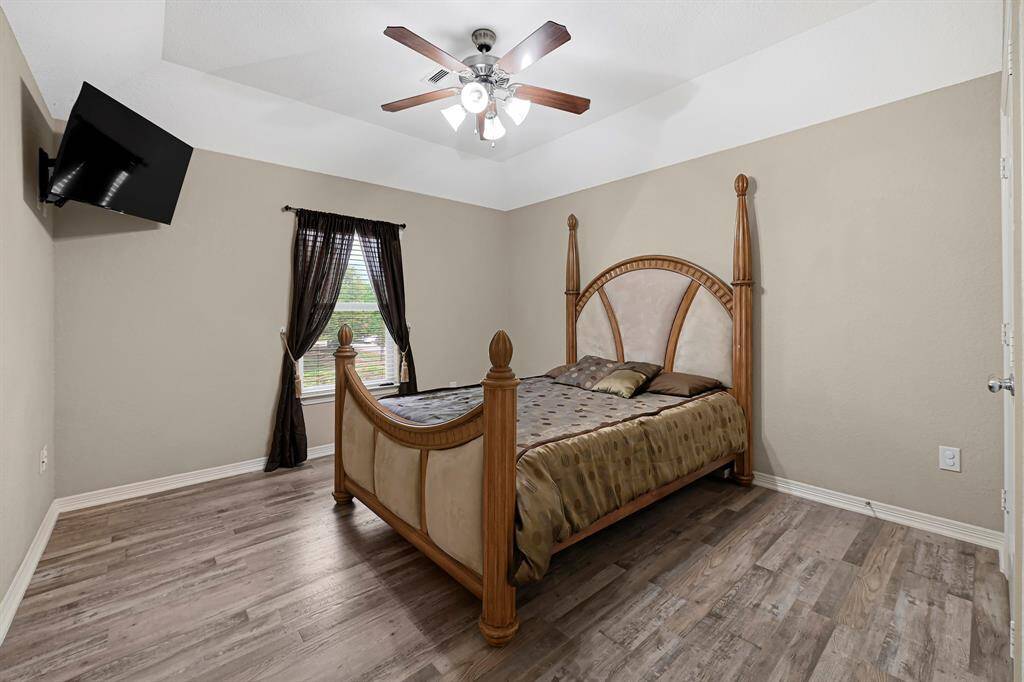Spacious upstairs bedroom with tray ceiling, ceiling fan, and generous natural light —perfect as a guest room or private retreat..
