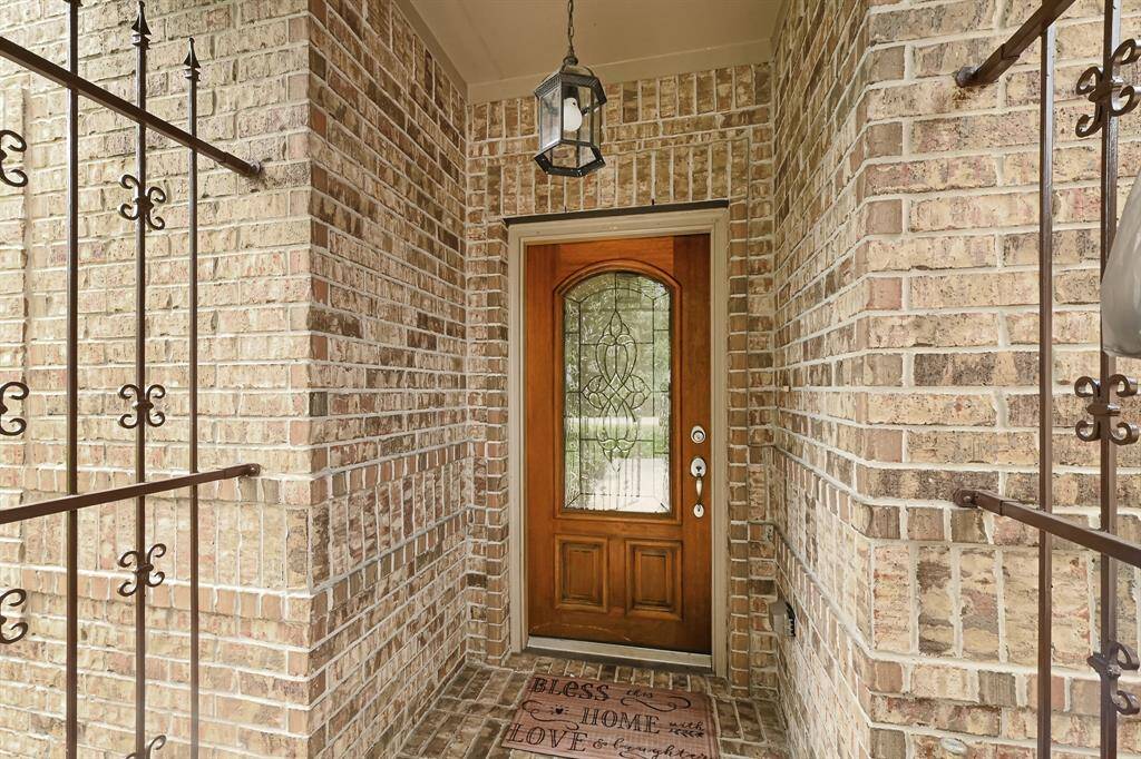 Charming covered front entry with wrought iron accents, and a beautifully crafted wood and glass door that welcomes you home.
