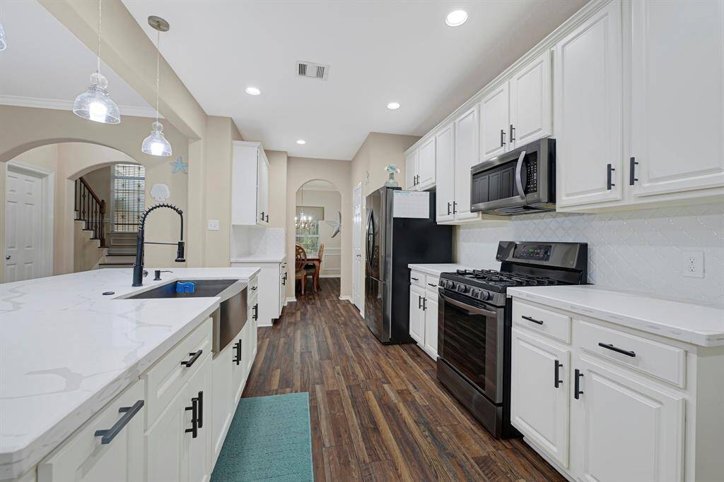 Modern kitchen featuring stainless appliances, pendant lighting, and a farmhouse sink.