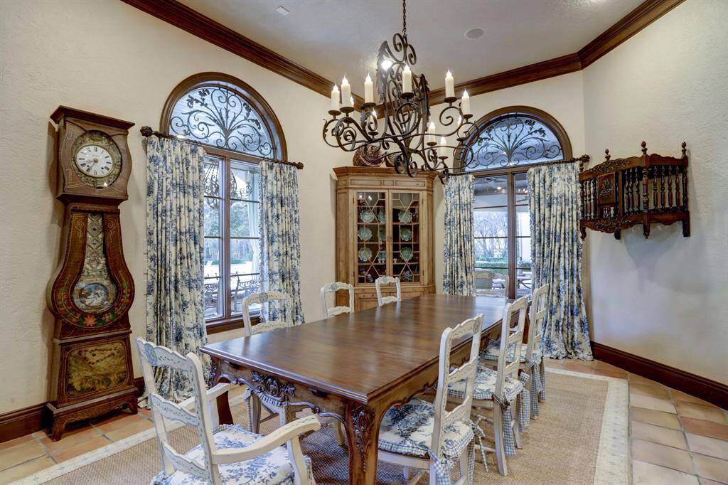 Casual dining room transitions seamlessly from family room is filled with natural light, featuring authentic terra cotta tile floors, crown molding, and an elegant chandelier.