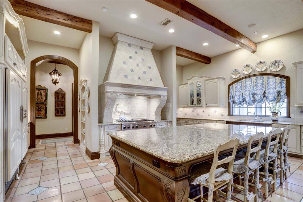 Intricate details adorn the kitchen including custom plaster vent hood and French hand-painted tile backsplash and reclaimed Saltillo tile floors.