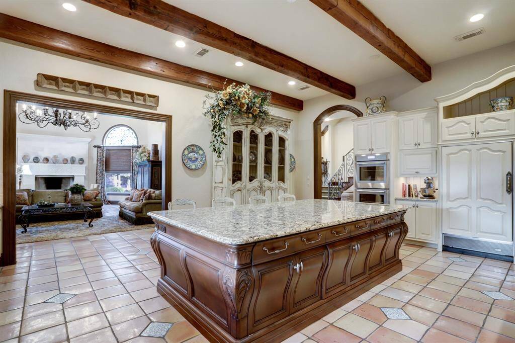 The spacious kitchen boasts a 55 sq.ft. granite island, SubZero appliances, a top-tier range, vintage wood beams, custom Osborne cabinets, and antique French terra cotta tile flooring.