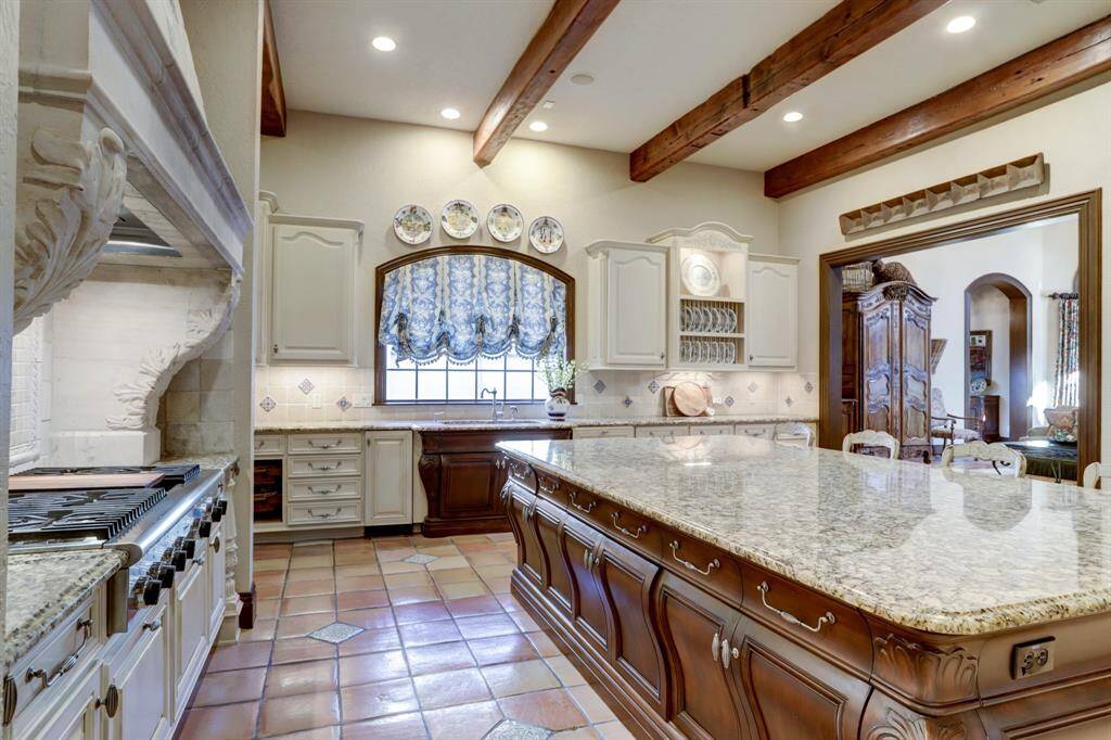 The chef's kitchen, graced with intricate French design, bombay custom cabinetry which offers a spacious 55 sq.ft. granite island, seamlessly transitioning into the den perfect for entertaining everyone.