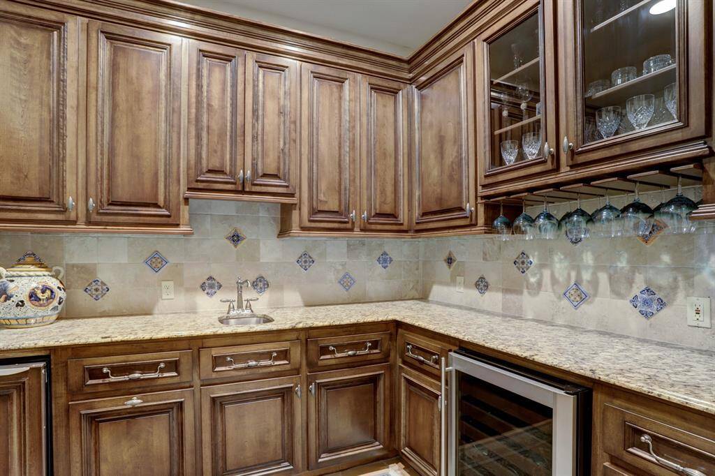 Butlers pantry equipped with wet bar includes plenty of storage and wine chiller.
