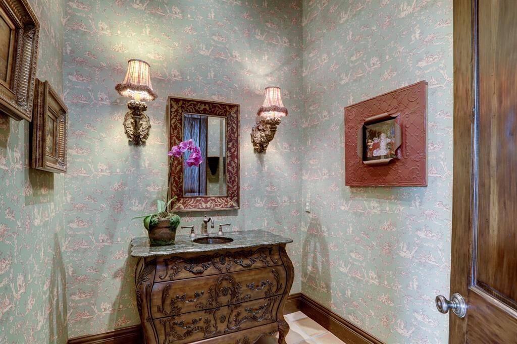 Large first floor powder bath with custom wall coverings, custom vanity and antique sconces.
