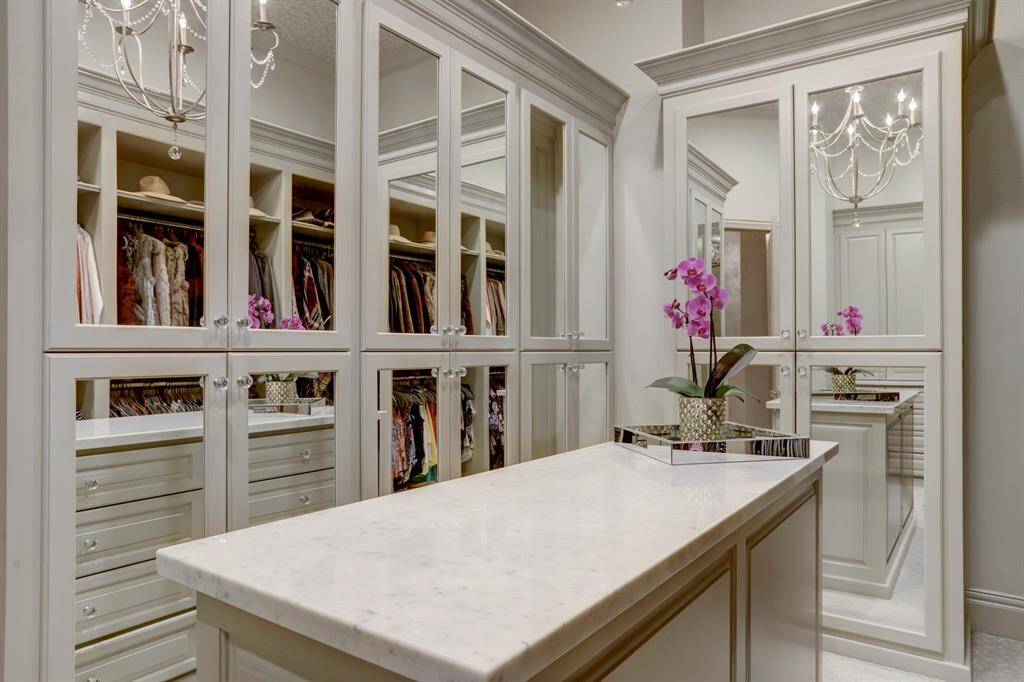 Custom primary closet featuring an island and mirrored cabinetry for added elegance and storage.