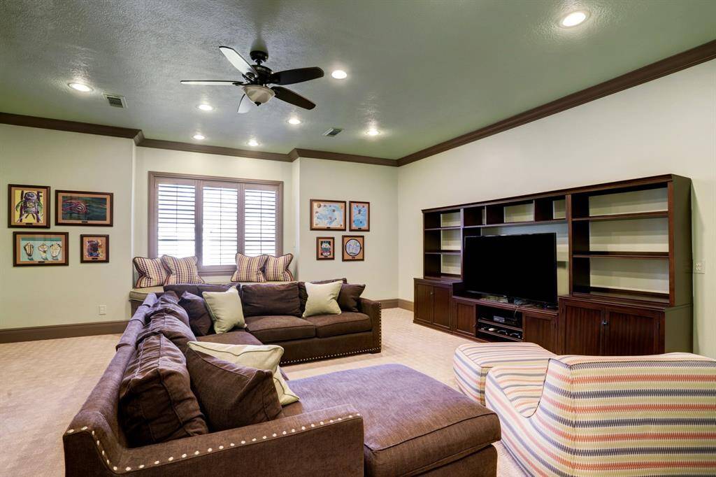 The secondary living space boasts elegant, stained plantation shutters, intricate crown molding, and tasteful recessed lighting. It's the perfect area to unwind and entertain guests in style.