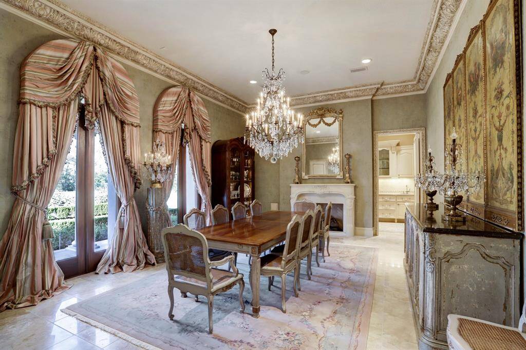 Exuding old-world French charm, the formal dining area epitomizes elegance with lavish crown molding, marble floors, crystal chandelier, and a fireplace, elevating the dining experience to unparalleled heights.
