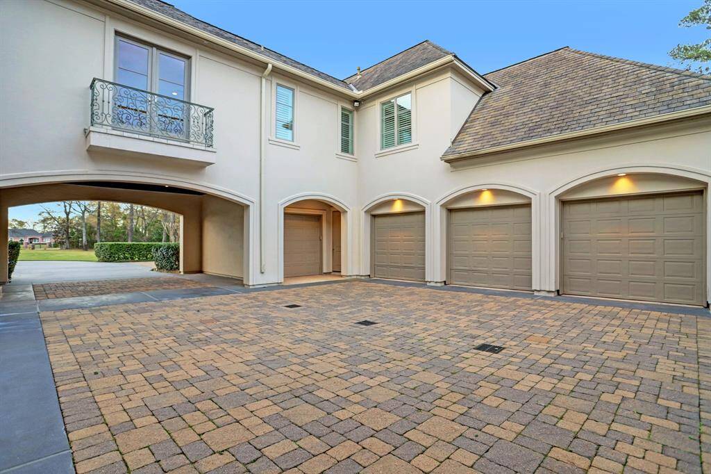 A spacious motor court, accessible through the porte-cochere, leads to an expansive garage area, offering ample space for parking and storage.
