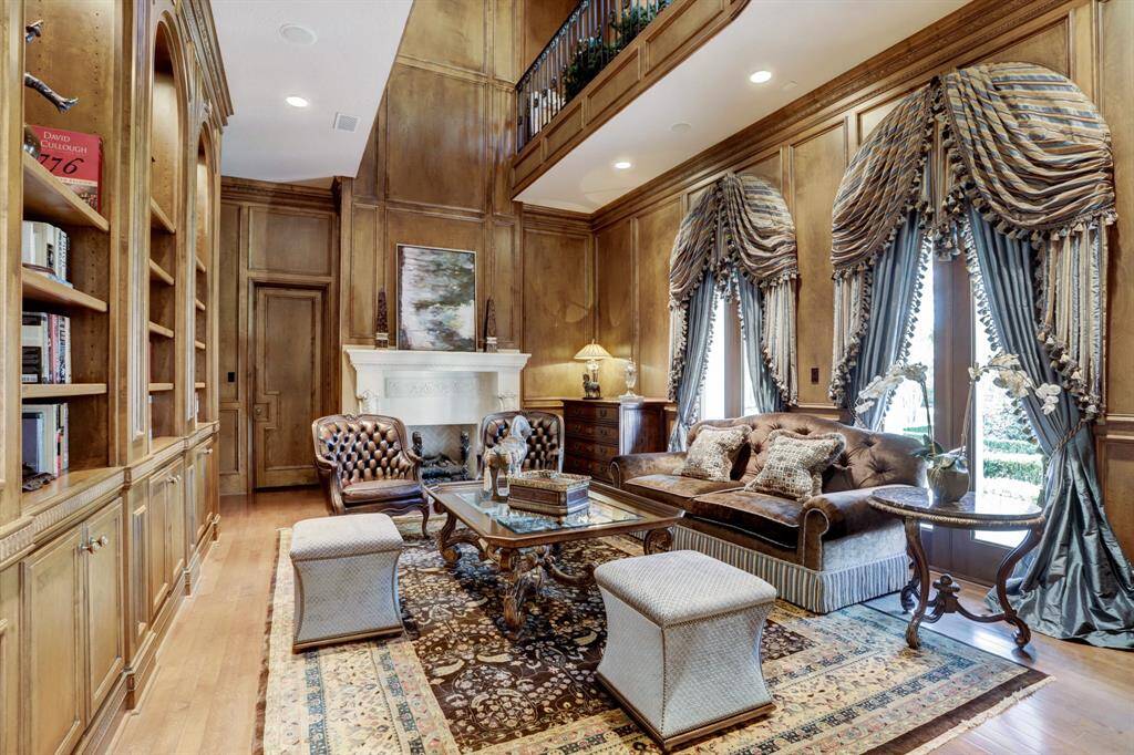 Paneled study with second floor library wrapped in detailed millwork, built-ins and grand stone fireplace.