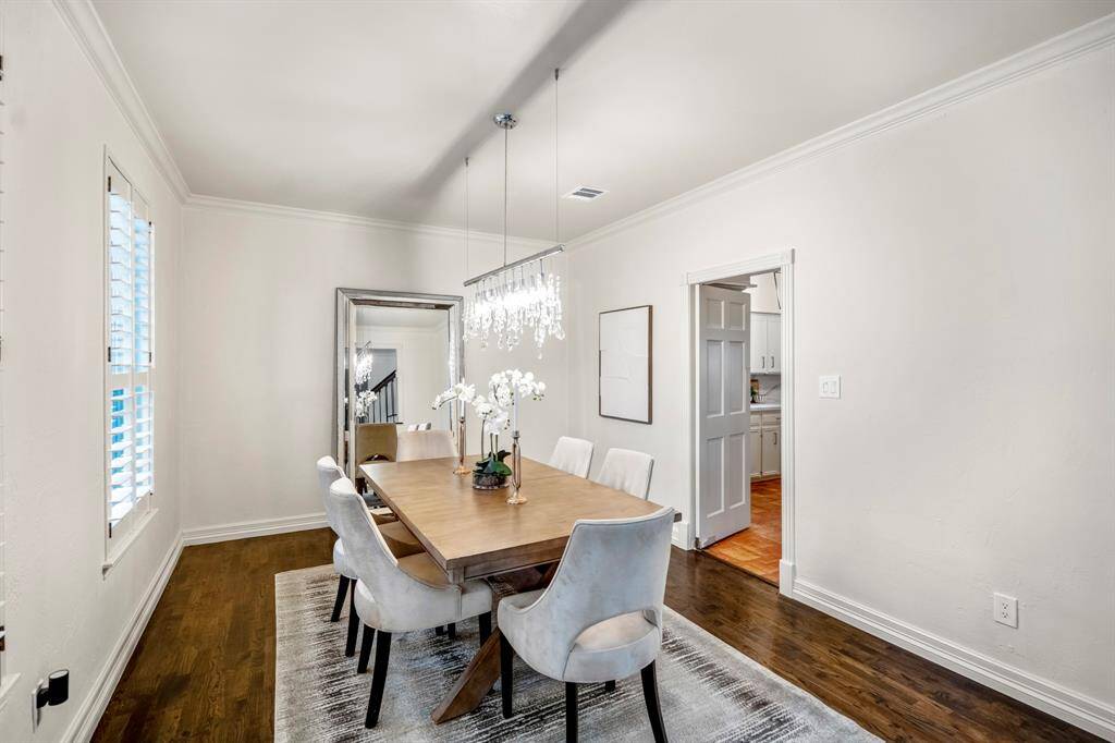 The formal dining room offers stylish lighting with a glass chandelier, doors to the kitchen, crown moldings and beautiful gleaming wood floors.