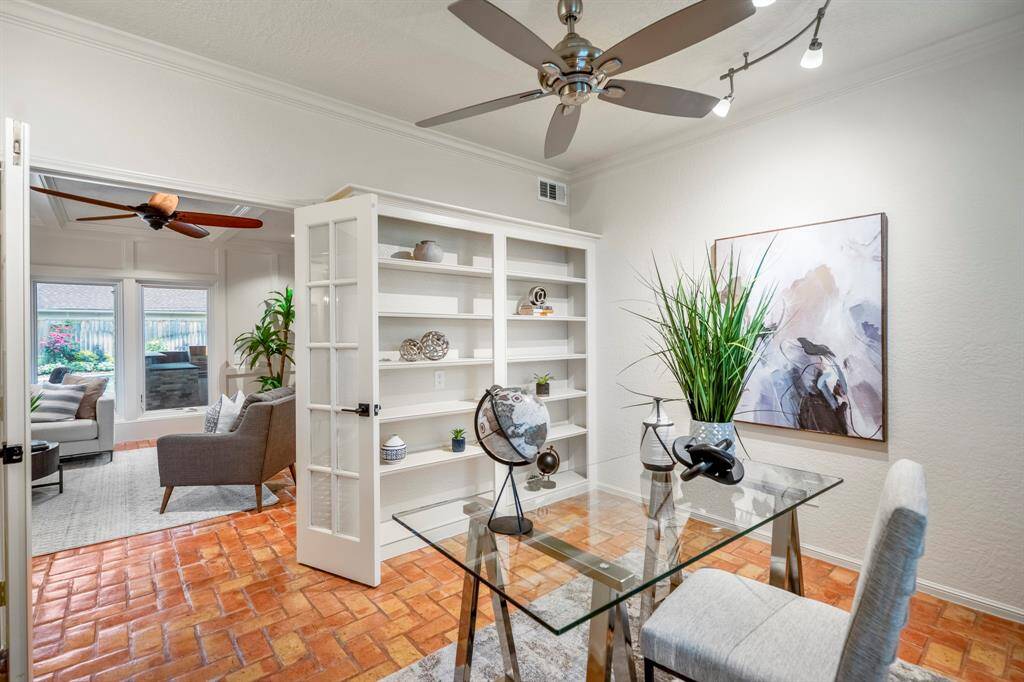 French doors lead into the work from home / study area, with custom built-ins, new ceiling fan, and custom lighting.