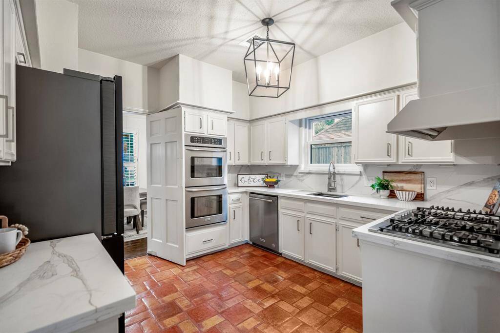 The kitchen features double ovens, custom lighting, a stainless steel sink, a gas grill and tons of cabinetry.