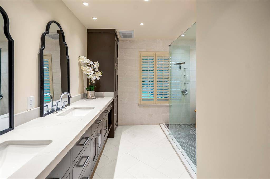 The primary en-suite bathroom offers dual sinks, wood look cabinetry with updated hardware and amazing glass enclosed shower.