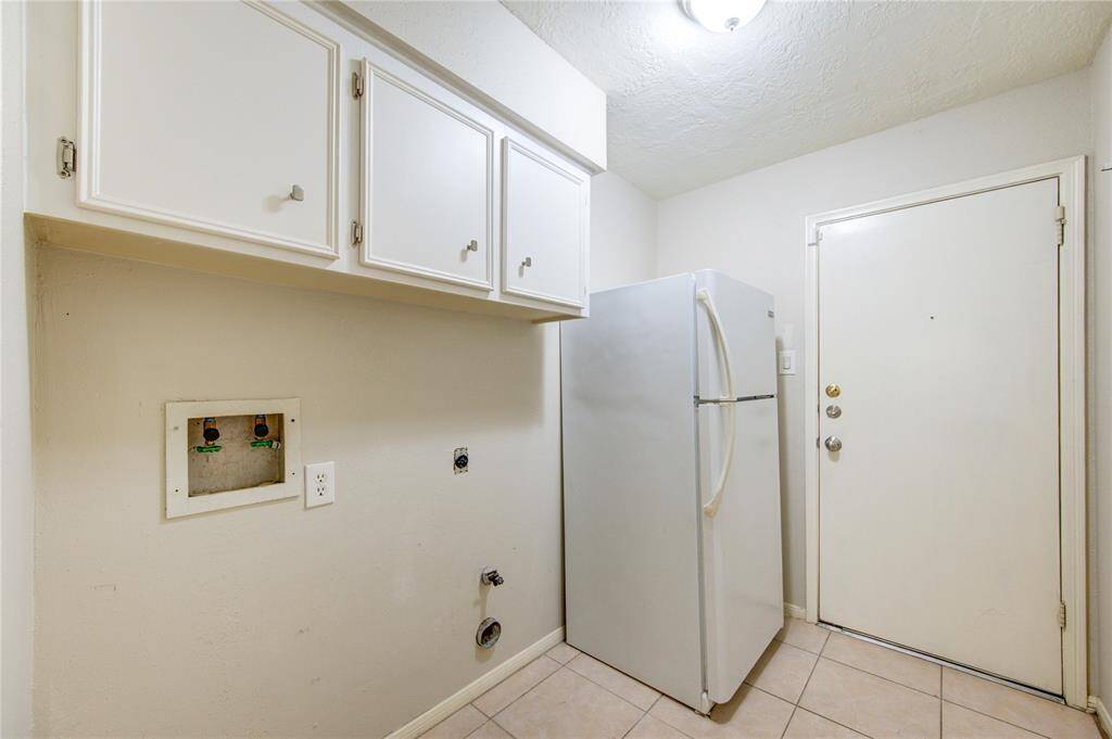 This roomy laundry area/utility room offers built-in storage and enough space for a full-sized washer and dryer, along with a secondary refrigerator or freezer.