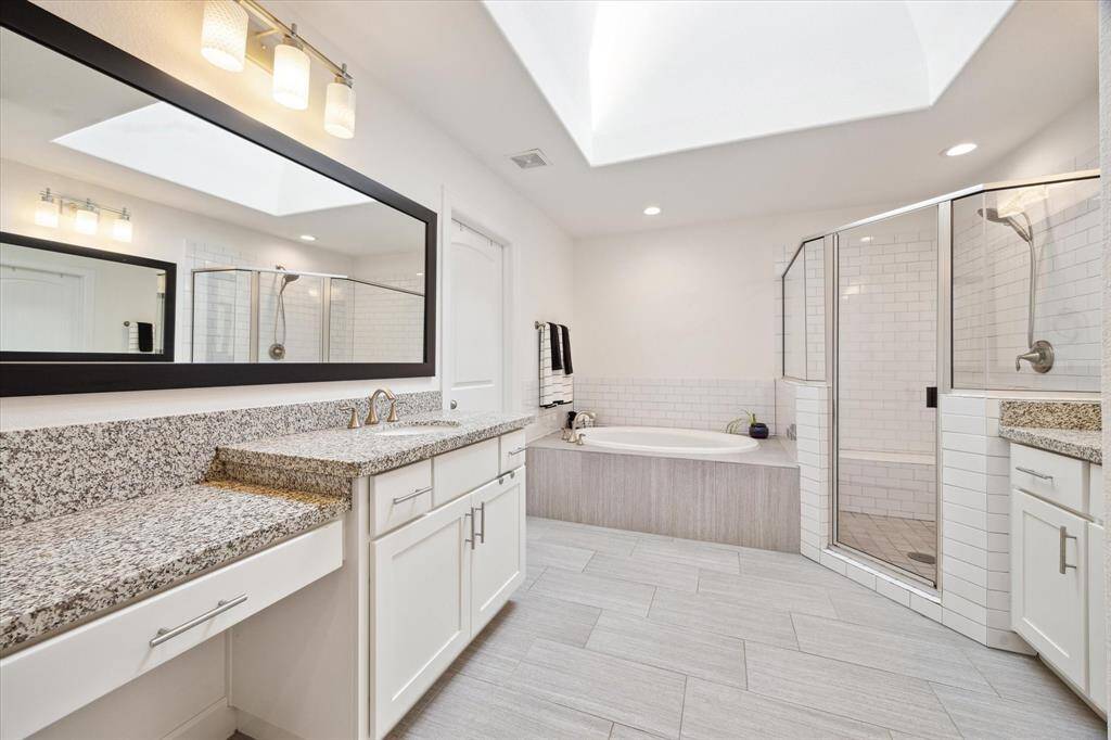 Primary Bath (16x10) offers skylight that brings in great natural light! Separate oversized shower, and 5 foot oval soaker tub. Left side offers seated vanity plus second sink. Porcelain tiled floors with subway accents.