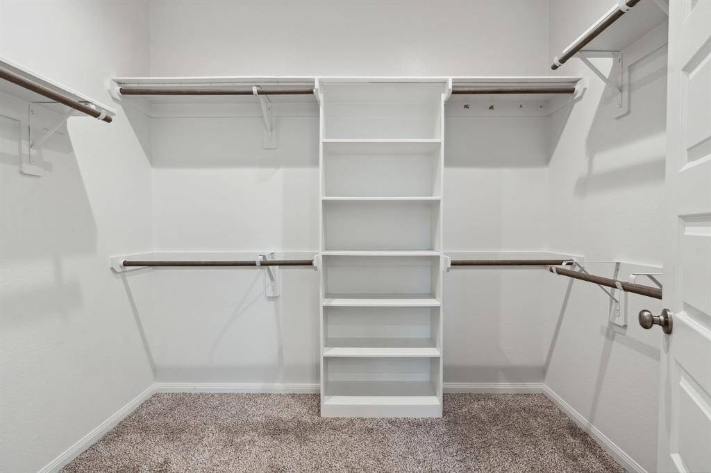 The first walk-in closet features plush carpet and plenty of storage space.