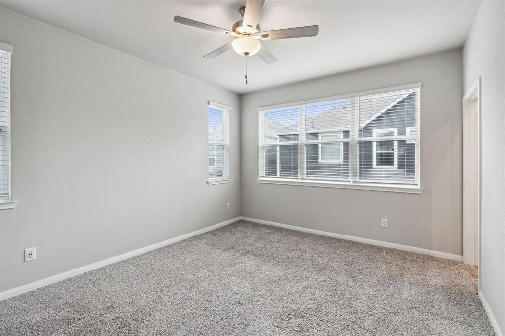 The second primary bedroom features plush carpet, large windows, and a ceiling fan.