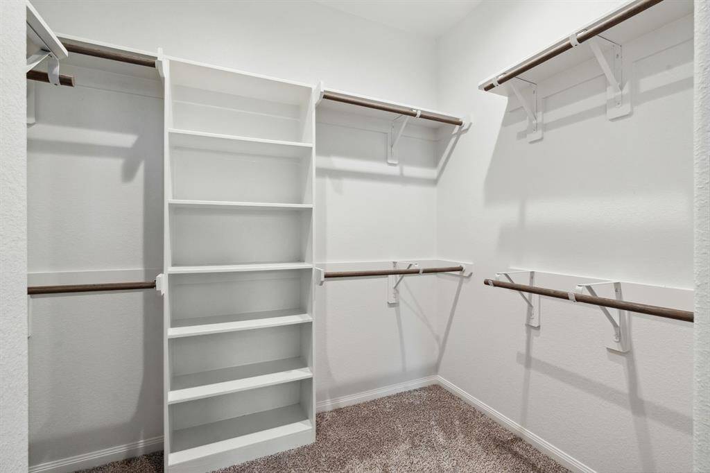 The second walk-in closet features plush carpet and plenty of storage space.
