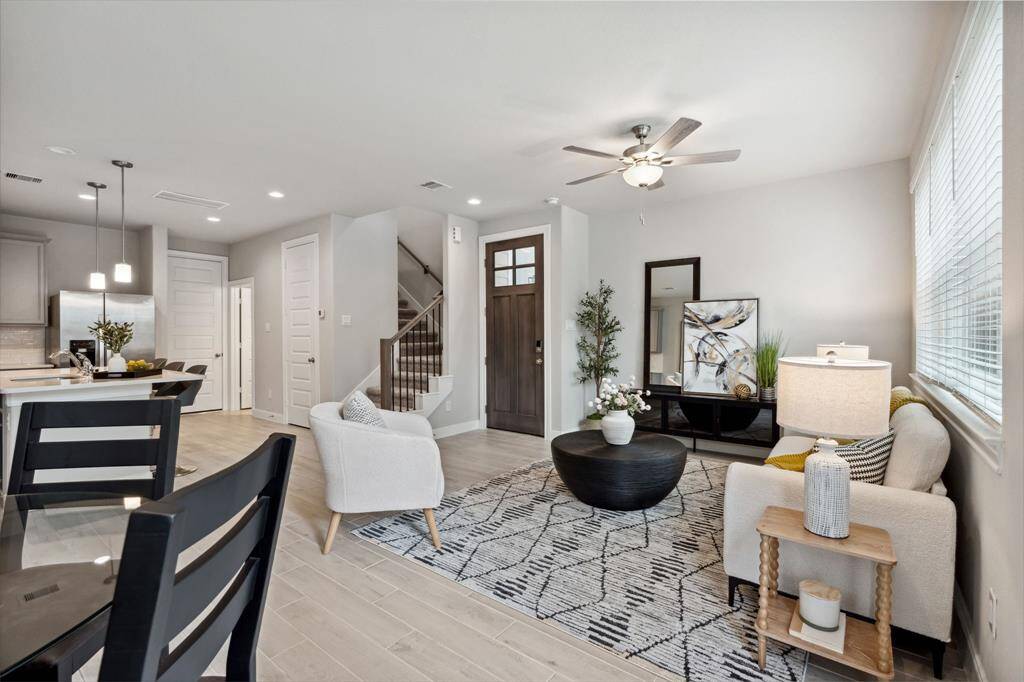 Living room features beautiful flooring, aceiling fan, and large windows.