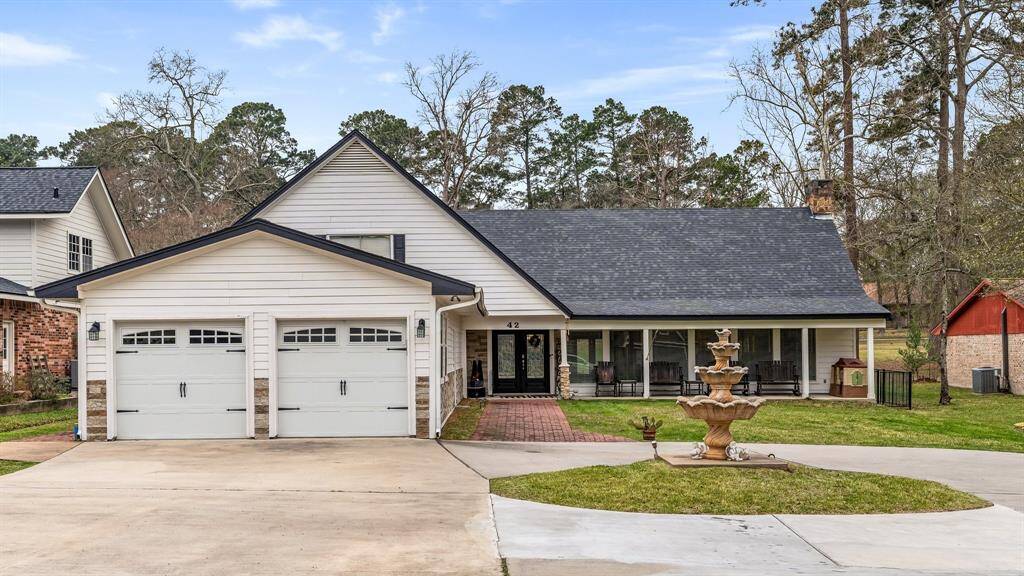 This welcoming home features a modern white exterior with a double garage and a charming front porch. The landscaped front yard includes a decorative fountain, offering a serene and inviting atmosphere.
