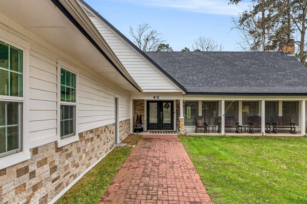 welcoming brick walkway and spacious front porch. The exterior showcases a combination of white siding and stone accents.