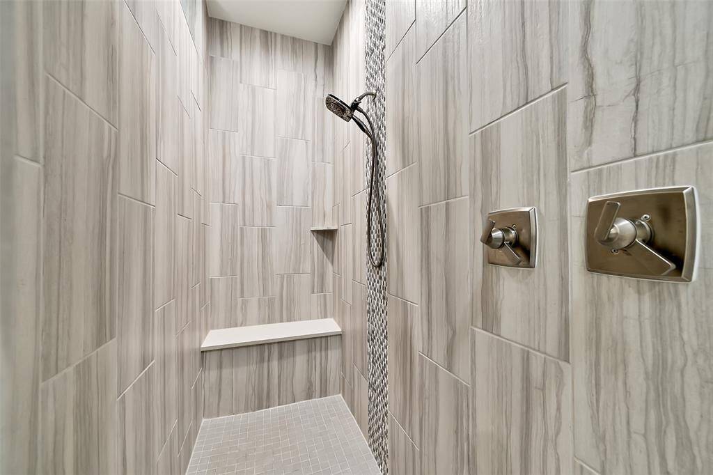 Walk in shower with floor to ceiling tile, rain head and detachable handheld shower head.