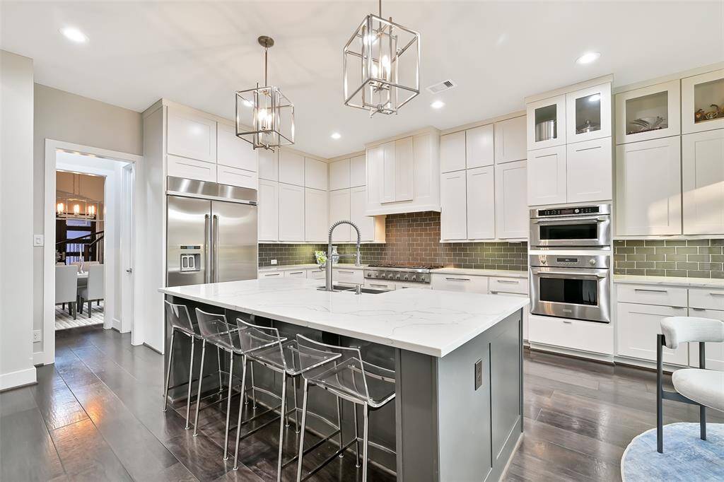 Chef's kitchen is sleek with large island, quartz countertops, soft close drawers, abundant storage, timeless pendant lighting, Thermador 5 burner range and ss appliances.