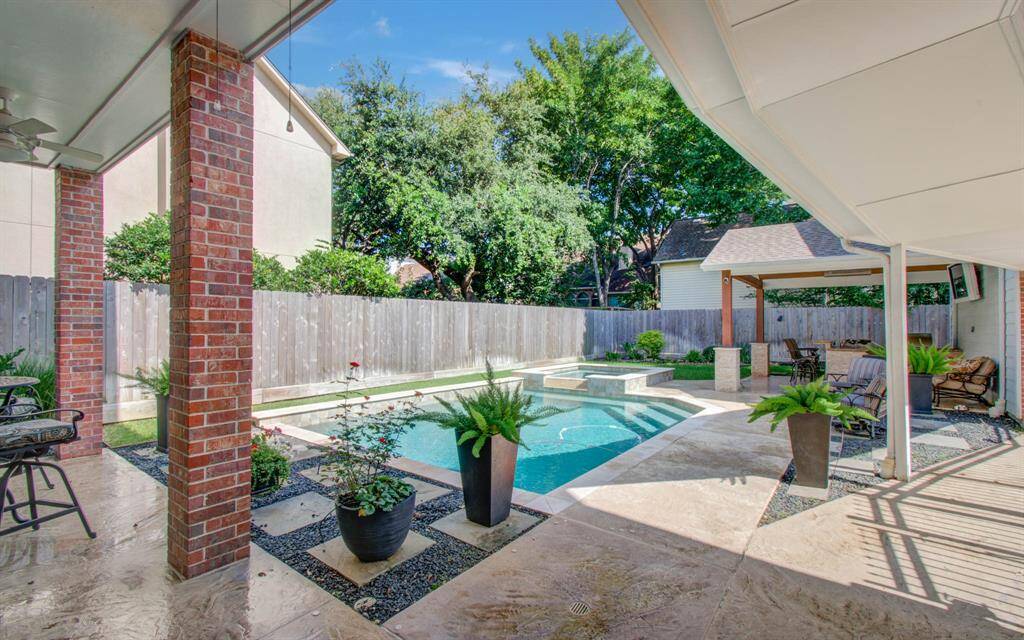 As you step out of the kitchen door you enter a covered patio area overlooking the pool. The walkway to the garage is also covered