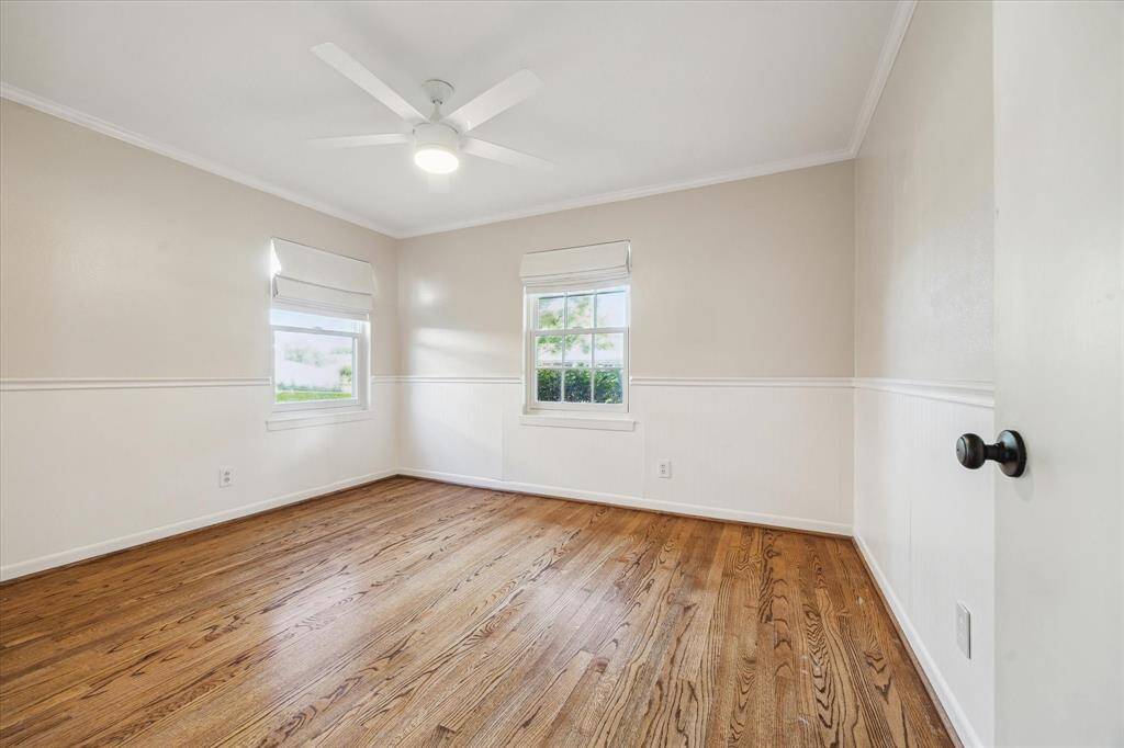 Secondary bedroom with wainscoting and custom window coverings.