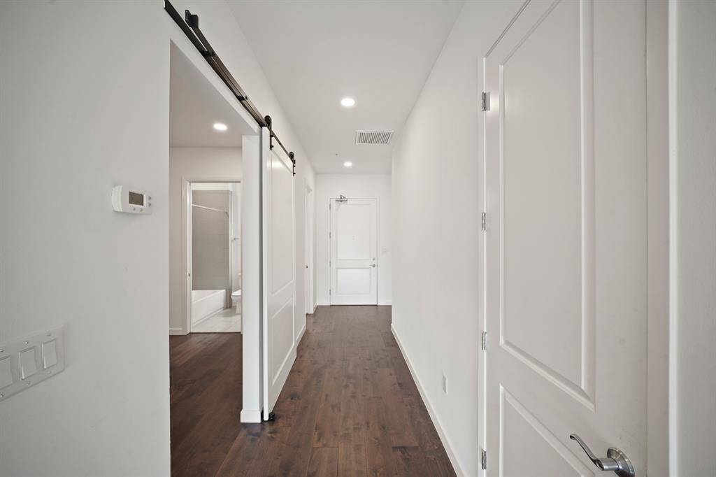 A view from the hallway looking towards the front door, secondary bedroom on the left, hall closet on the right.