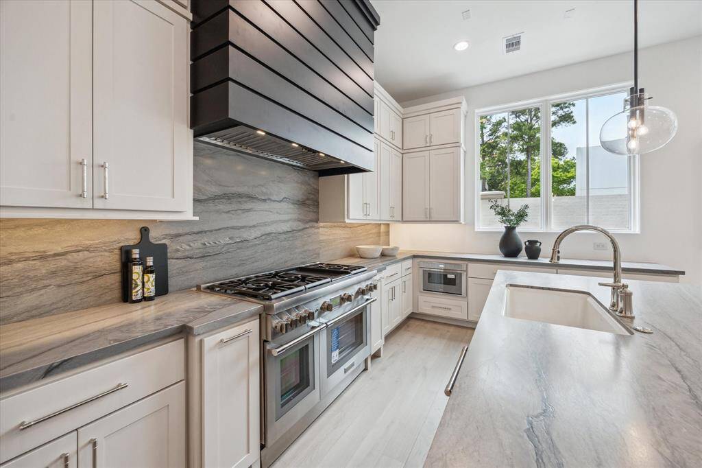 Leathered Blue Tahoe Quartzite waterfall island and undermount Porcelain sink with Kallista faucet complete this luxury kitchen. Ample prep space, storage space, and island seating make this space functional and stunning.
