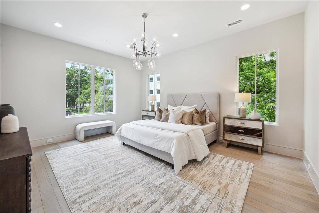 The Primary Suite is adorned with 10-foot ceilings and a designer light fixture. Exquisite Legno Bastone European White Oak wood floors continue in this space adding to its overall elegance and charm.
