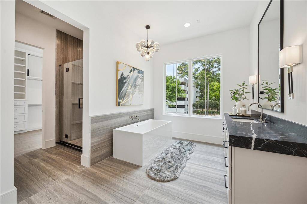 Primary bathroom features a Sterling Unwind freestanding rectangle soaking tub with Kallista One wall-mounted faucet, framed glass shower with Laticrete shower system, and two separate vanity areas.