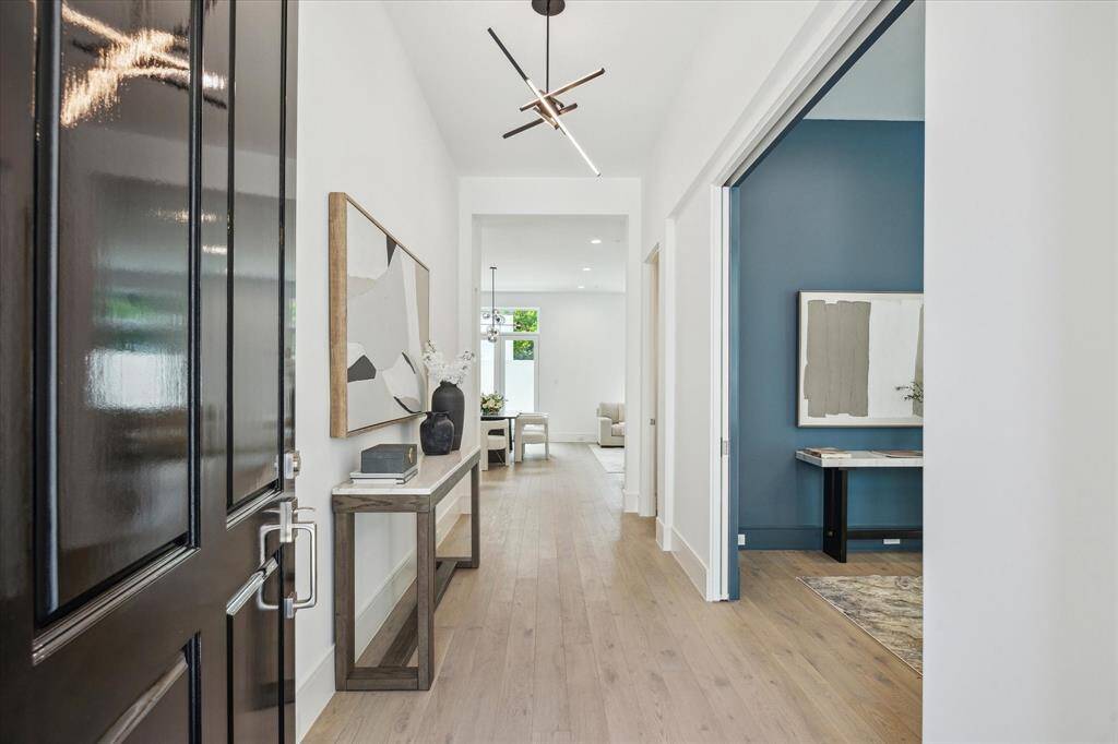 Step into this bright and welcoming formal entry. The first floor living space features 11-foot ceilings, Legno Bastone engineered White Oak wood floors, and designer light fixtures.