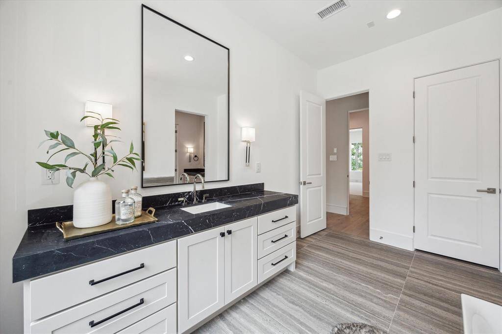 Custom Benedettini cabinetry, Nero Marquina Marble countertops, Kallista Perfect under-mount centric rectangle sinks with Kallista One contemporary fixtures, polished nickel and matte black sconces complete this elegant and serene primary retreat.