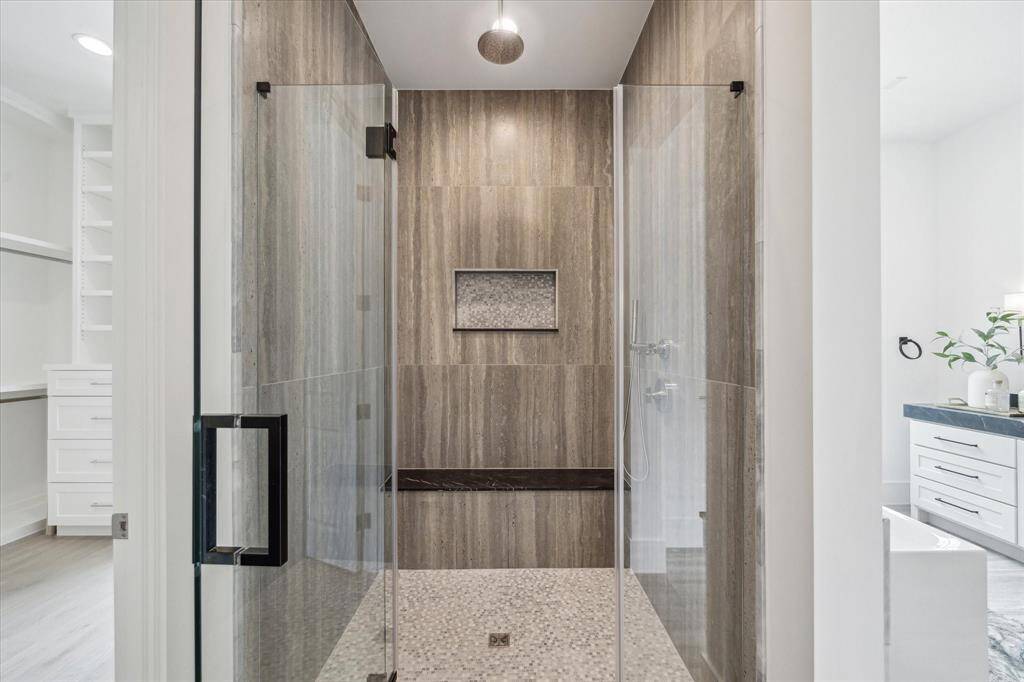 Framed glass shower with mosaic floor and niche design and Nero Marquina Marble bench create a cohesive space.