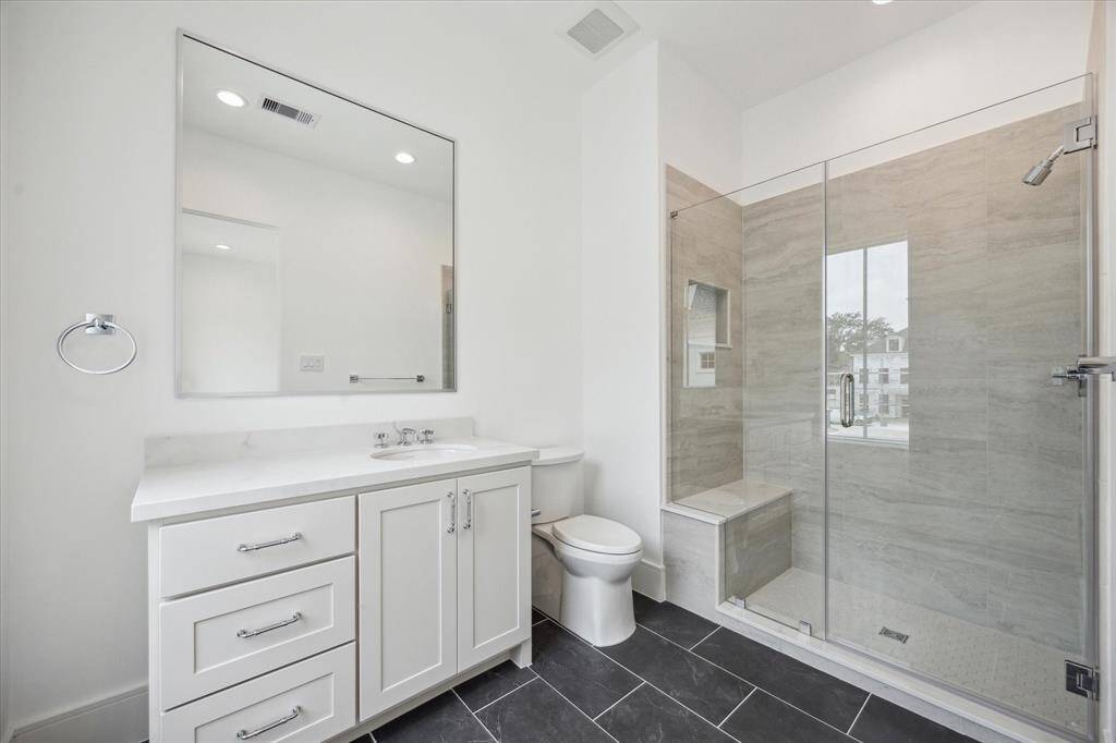 En-suite bathroom for final second-floor bathroom features a sleek, glass-encased shower, Quartz counters and additional counter and storage space.