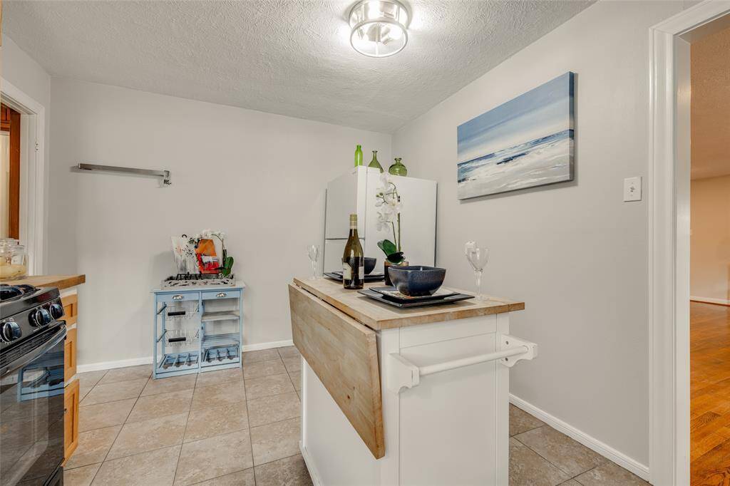 Kitchen with light wooden cabinets, white dual sink, gas cooker, microwave, dishwasher, movable center island