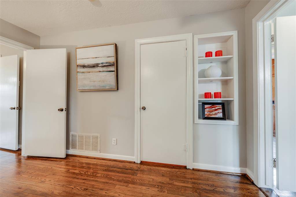 Primary Bedroom to the back of the home, hardwood floors, en suite bathroom, shelves for storage, large closet