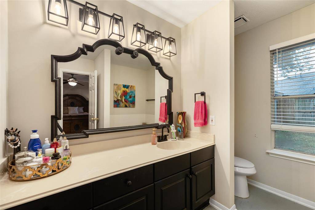 In the en-suite, expansive counters, bold black cabinetry, and a unique framed mirror bring character to the space.