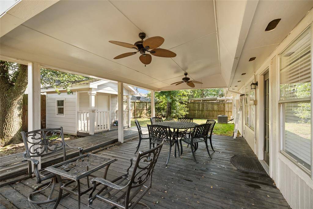 The expansive covered back deck features two ceiling fans and a storage building, with black decking and a crisp white cover that echo the home’s interior palette—a quiet, functional outdoor extension of the living space.