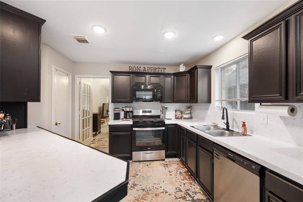 The kitchen features black cabinetry, stainless steel appliances, and recessed lighting—creating a functional workspace with a sleek, modern edge.