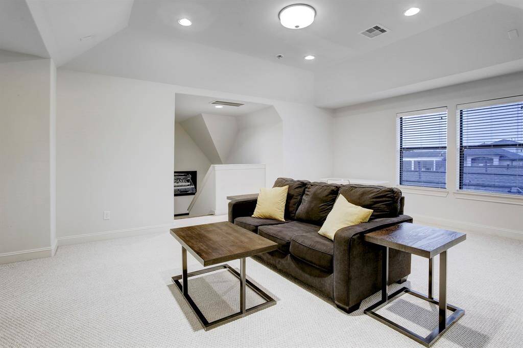 The large 3rd Floor Game Room (or 4th Bedroom) has a sleeper sofa with side tables, a coffee table, a wall-mounted TV, large windows, a raised ceiling with recessed and overhead lighting, and an ensuite full bath and walk-in closet.