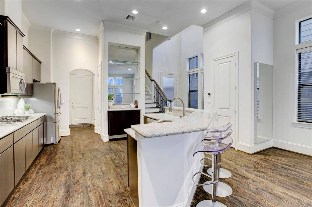 Gourmet Kitchen with gas cooktop, wall oven, French door refrigerator, sizable breakfast bar, granite countertops, and plenty of storage.  Walk-in pantry is behind a door across from refrigerator.  Notice the natural light from plentiful windows and under cabinet lighting.