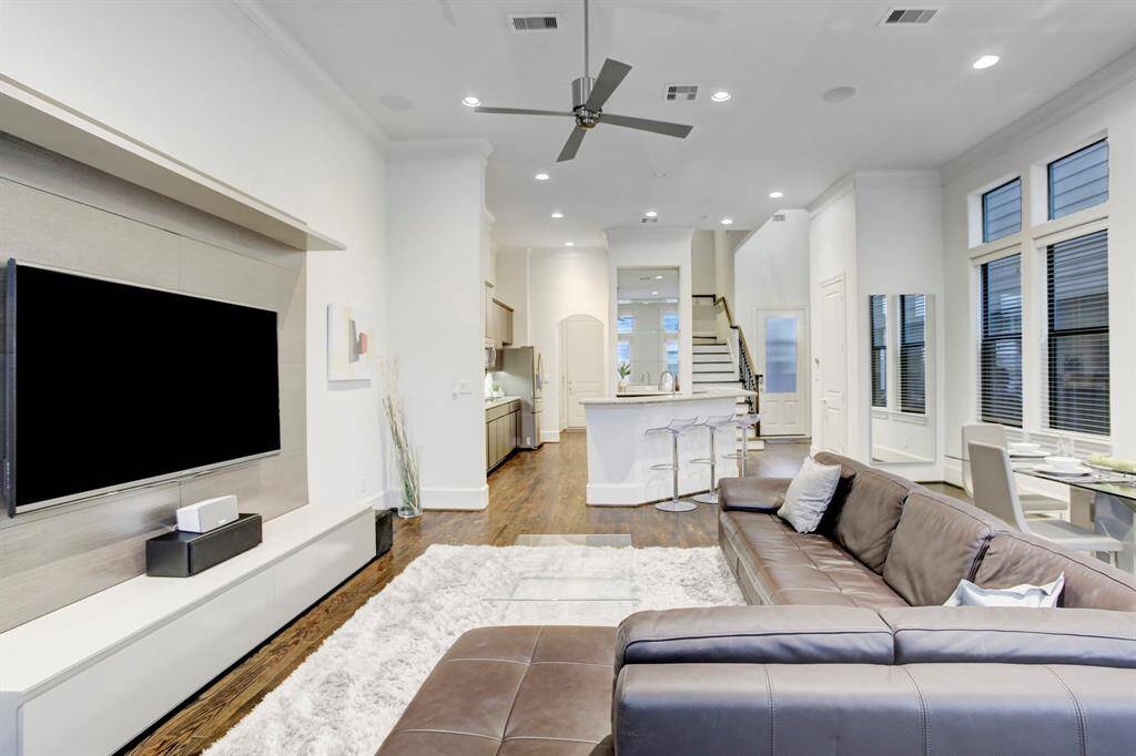 Living Area with sizable TV, gleaming hardwood flooring, comfortable furnishings, recessed lighting & ceiling fan.  Open to Kitchen and Dining Area.