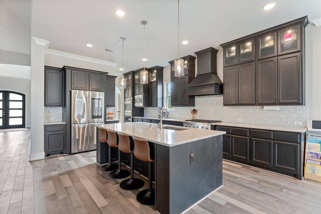 The gourmet kitchen features a spacious island with breakfast bar and pendant lighting, perfect for meal prep or casual dining. Sleek quartz countertops offer both elegance and practicality!