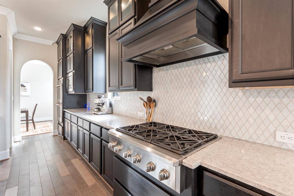 The double oven and 6-burner gas cooktop offer the perfect setup for preparing meals with ease, while the custom backsplash adds a unique touch of elegance and charm. Whether you're cooking for a crowd or enjoying a quiet meal, this kitchen effortlessly combines beauty with practicality.